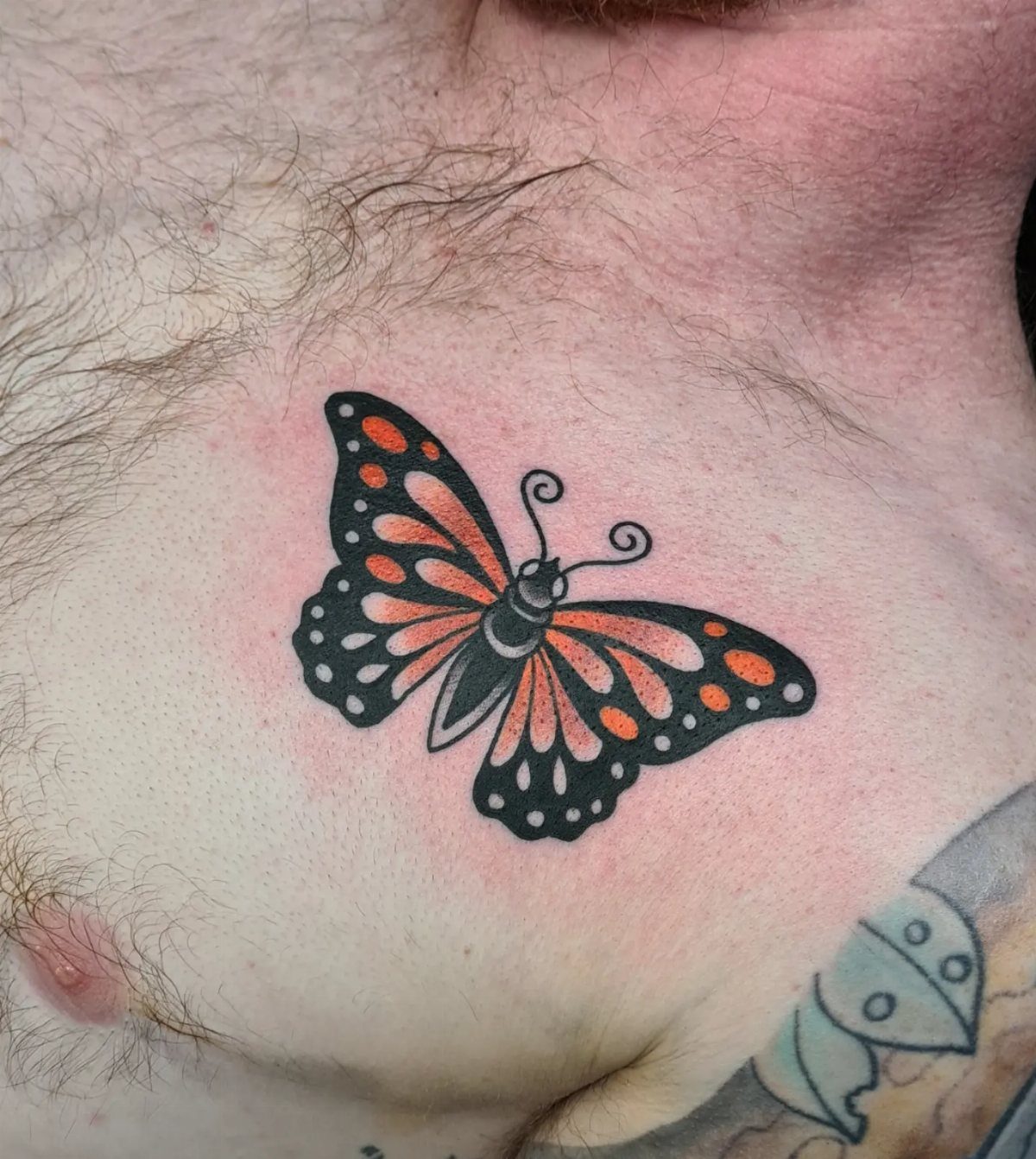Monarch butterfly tattoo with orange and black wings on a person's chest