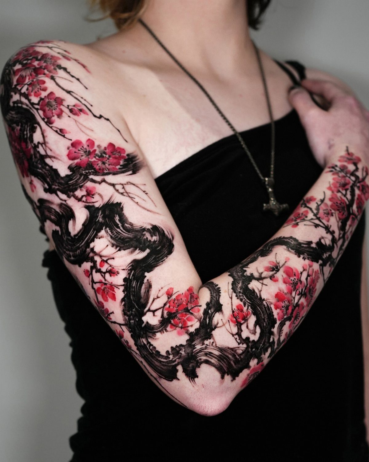 Dragon tattoo with pink cherry blossoms covering a person's entire arm