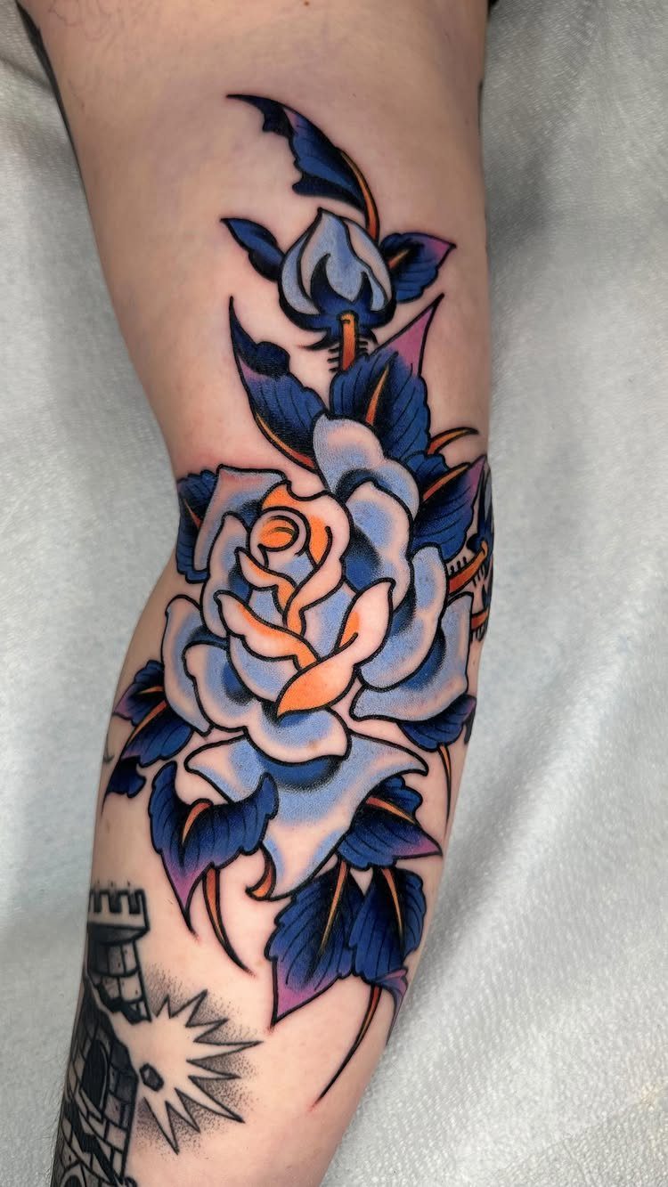 Blue and white rose tattoo with bold outlines on a person's forearm.