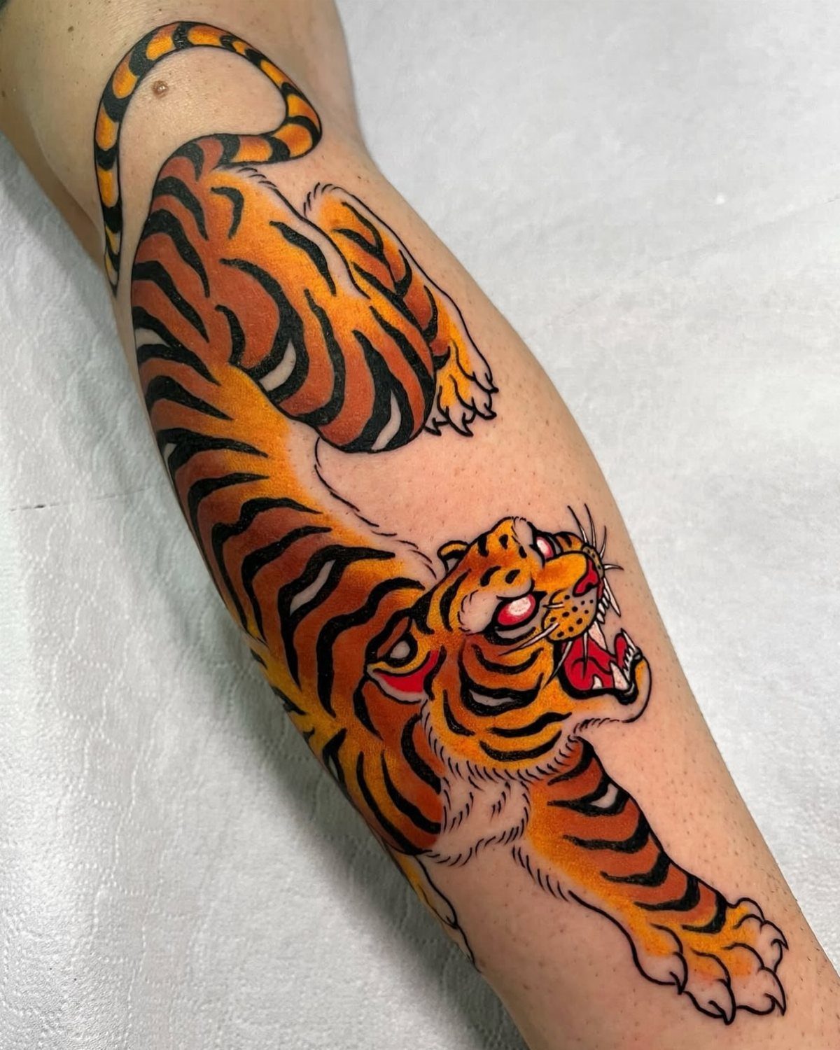 Traditional Japanese tiger tattoo with orange and black stripes on a person's arm.