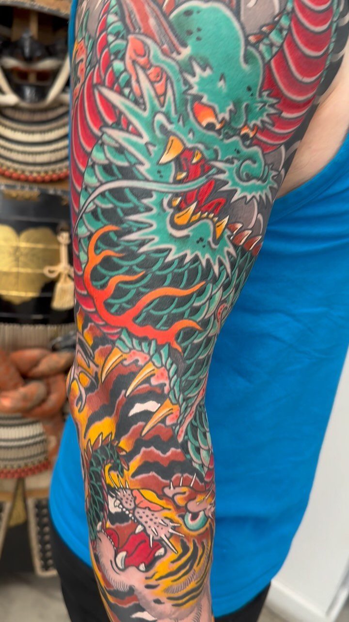 Japanese style tattoo sleeve featuring a green dragon and a tiger on an arm