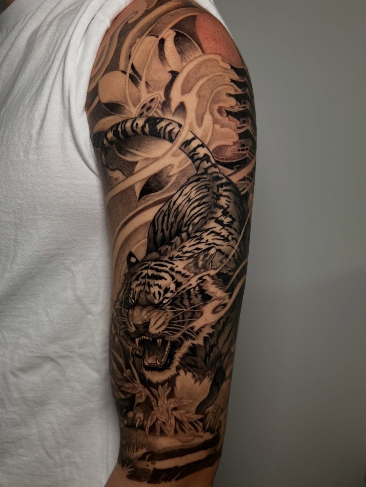 Roaring tiger tattoo in traditional Japanese style on a person's upper arm.