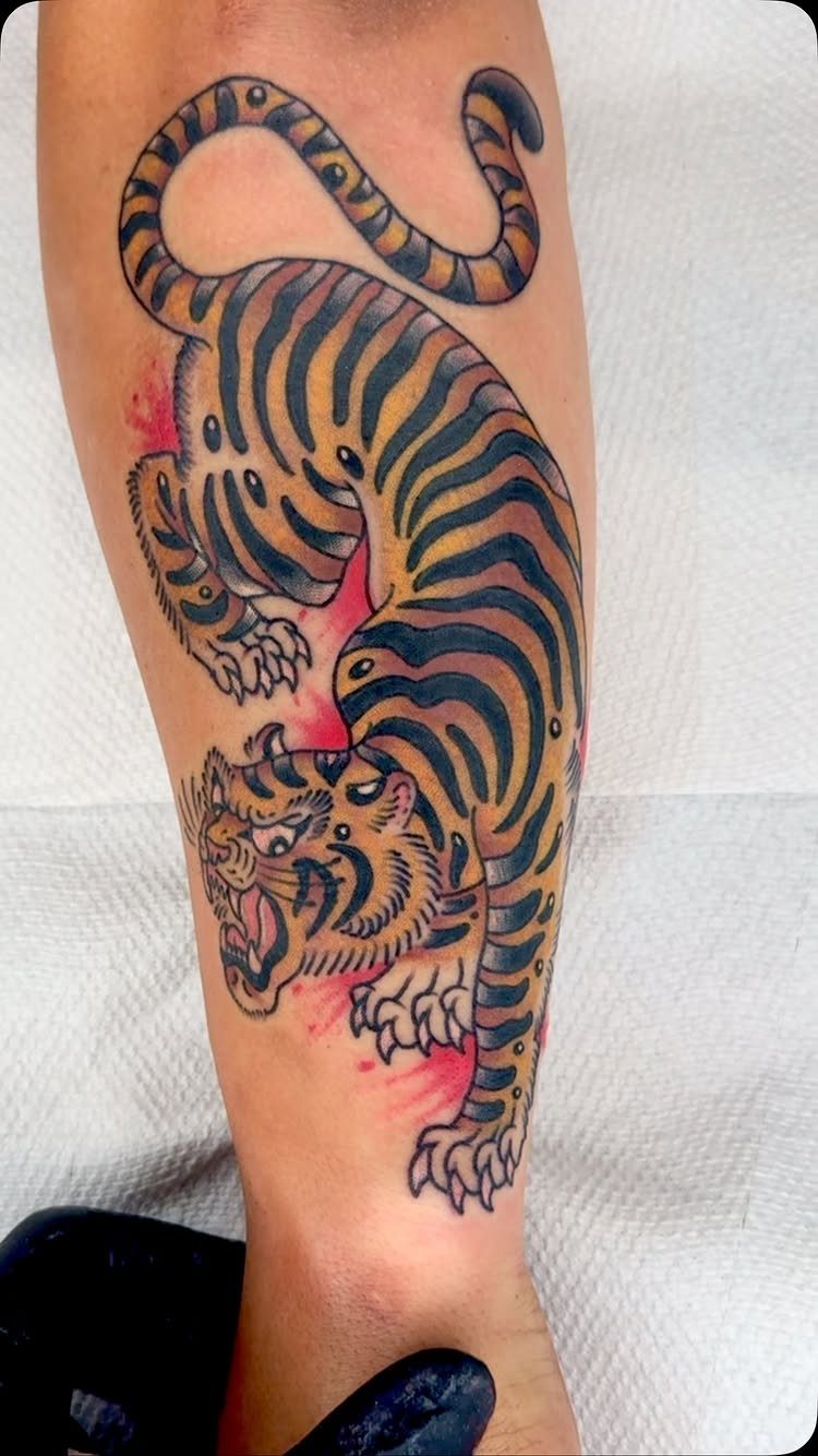 Traditional Japanese tiger tattoo with orange and black ink on a person's leg