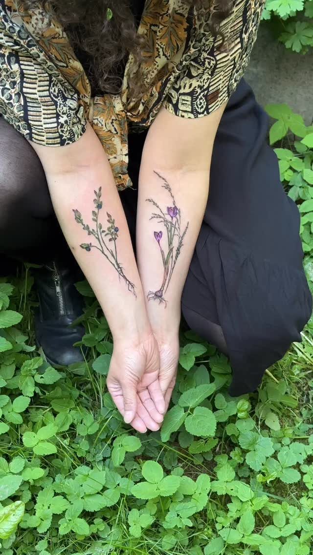 Wildflower tattoos on forearms with small purple blossoms and thin green stems.