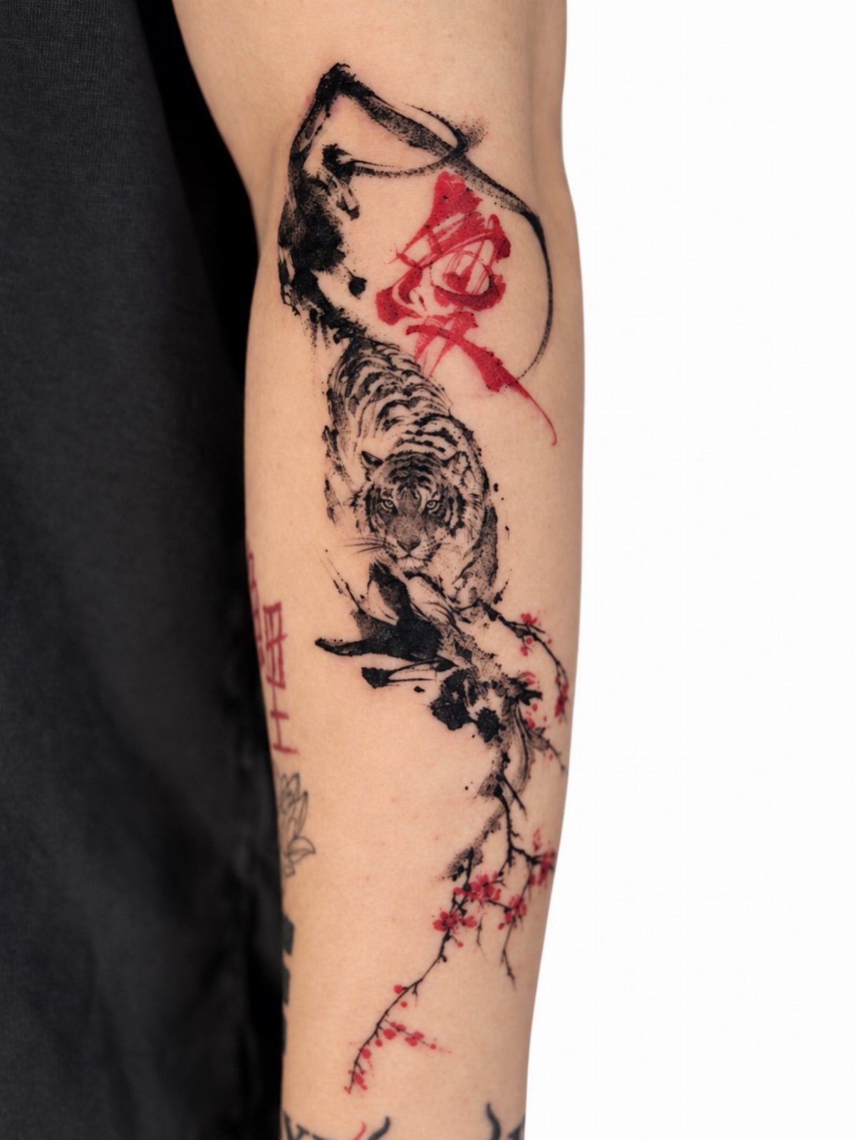 Tiger tattoo in ink wash style with red calligraphy and cherry blossoms on arm