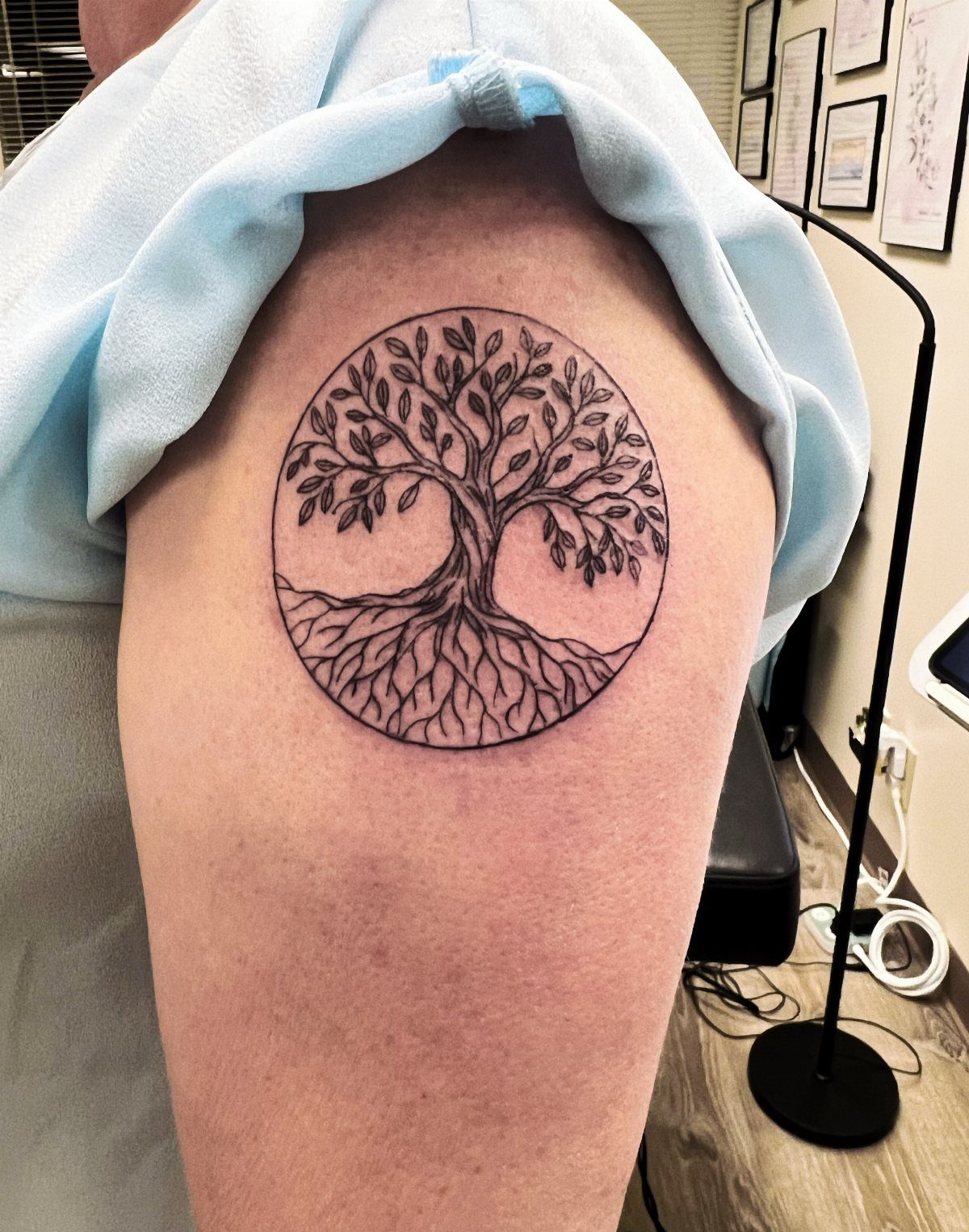 Tree of life tattoo with intricate roots and branches on an upper arm