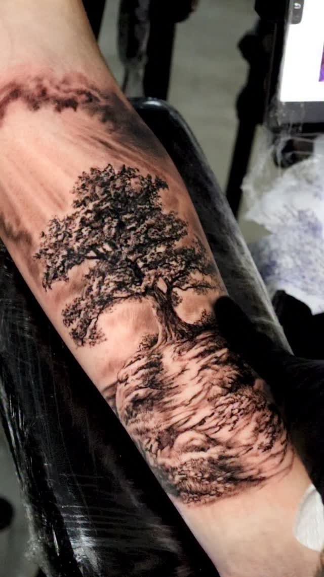 Detailed black and grey tree of life tattoo on a person's forearm
