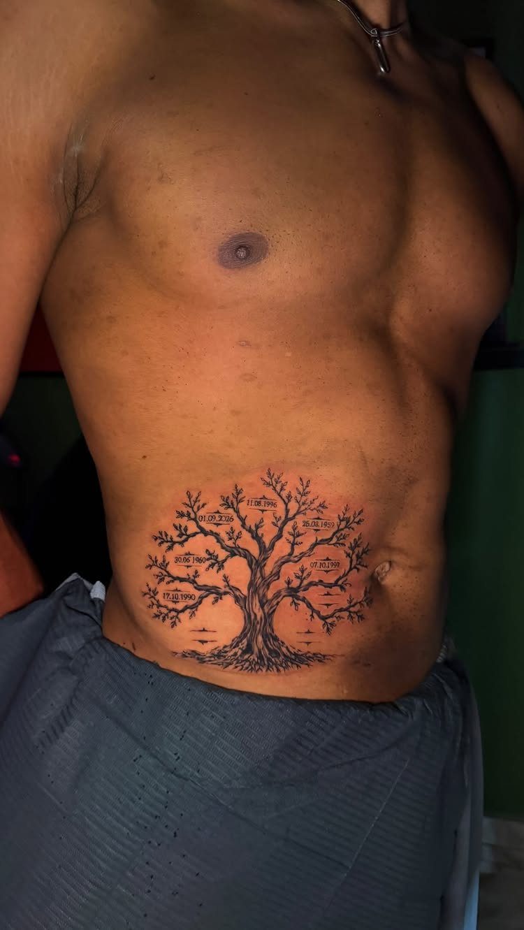 Tree of life tattoo on a man's torso featuring names in the branches.