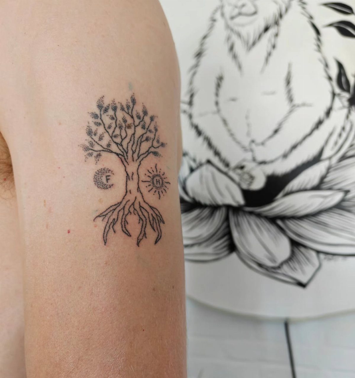 Tree of life tattoo on an arm with a sun and crescent moon.
