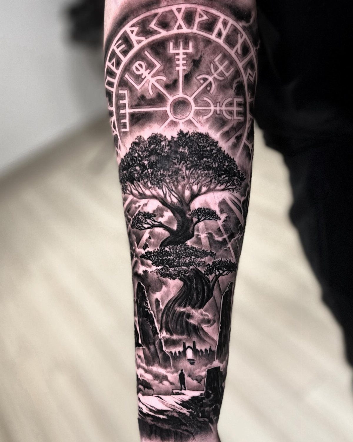 Detailed black and grey arm tattoo of Yggdrasil with a Norse runic compass.
