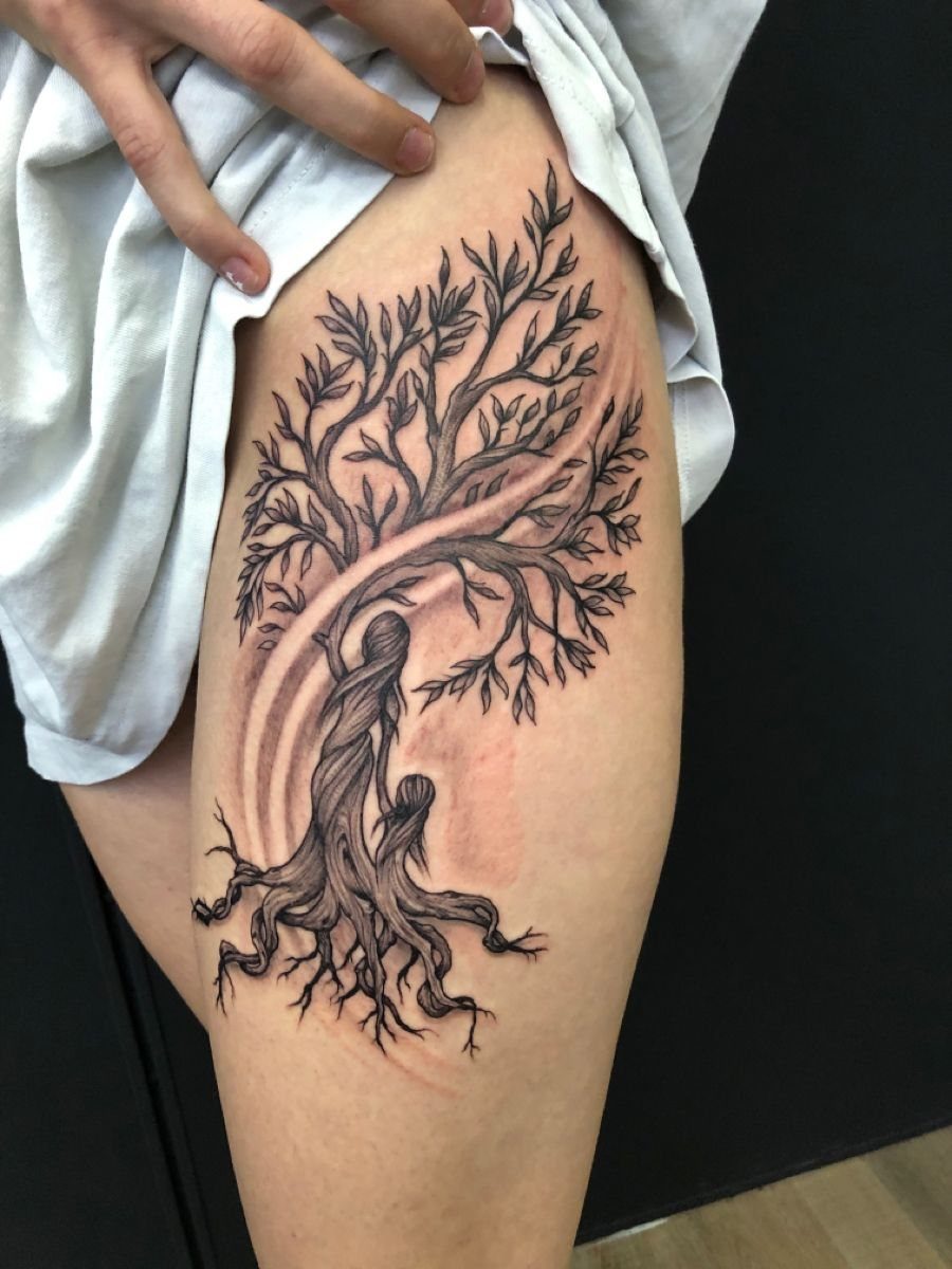 Willow tree tattoo on a thigh featuring figures of a mother and child.